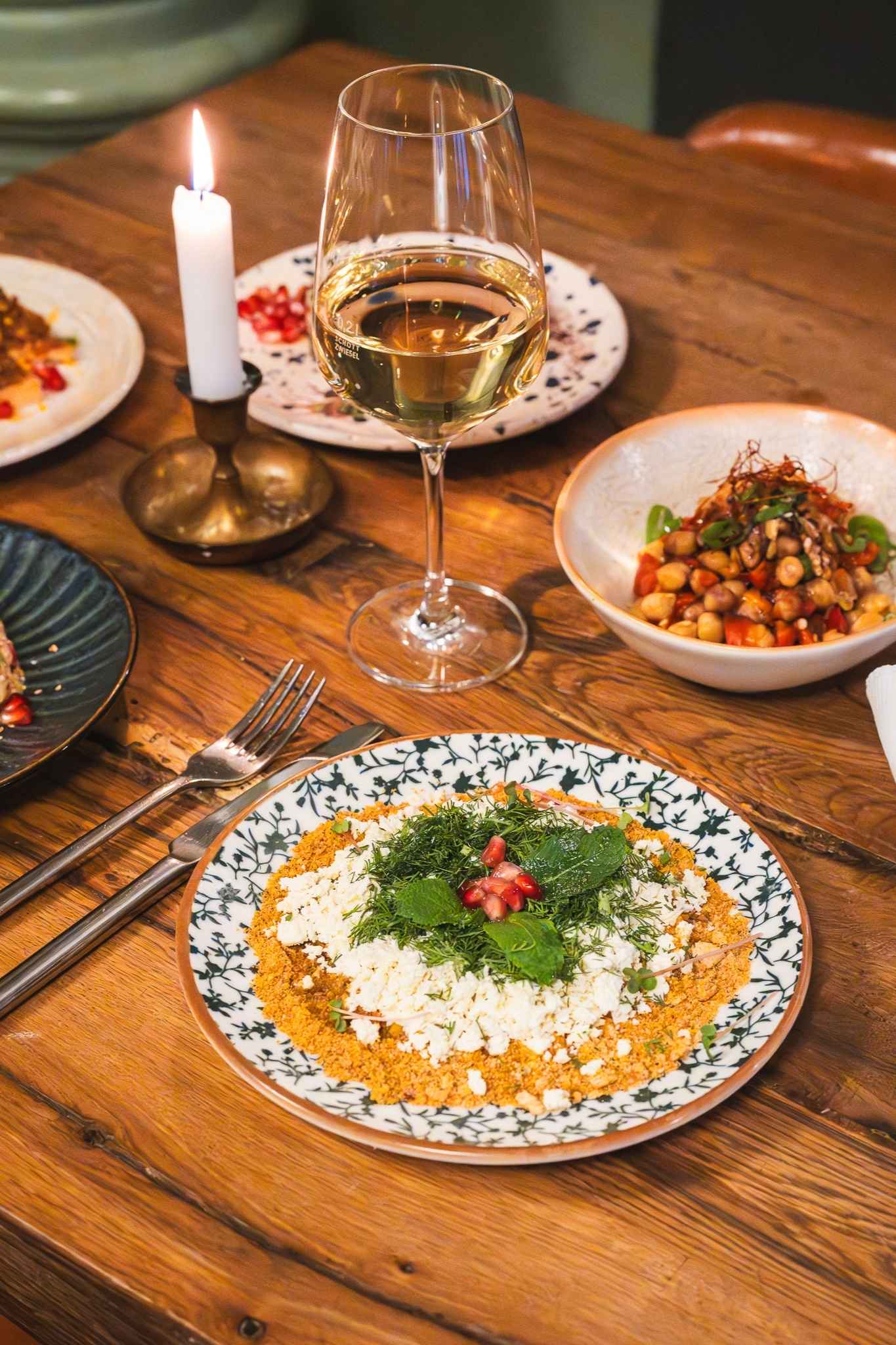 Teller Arragement mit veganen Gerichten und einem Glas Weißwein