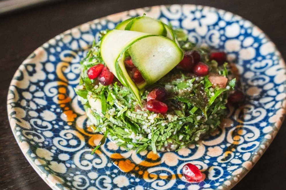 Ansicht eines veganen Gerichts serviert mit vielen frischen Kräutern und modern interpretiert